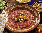 Gazpacho auf Keramikteller mit Gemüsewürfeln und Croûtons