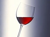 A glass of red wine held at an angle