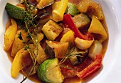 Ratatouille with thyme and rosemary on white plate