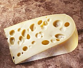 A piece of French Emmental cheese on brown background