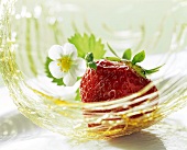 A strawberry with strawberry flower in a basket of caramel strands