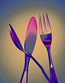 Gabel, Messer und Löffel in rosa-blauem Licht