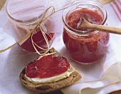 Strawberry jam in two jars and on bread