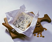 A piece of Bleu d Auvergne with paper on a chopping board