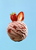A scoop or strawberry ice cream with strawberry pieces