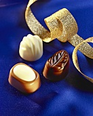 Three chocolates on blue silk with ribbon