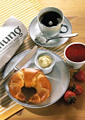 Breakfast with coffee, croissant, butter, strawberry jam