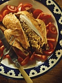 Stuffed chicken with rice, halved, on plate with tomatoes