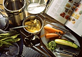 Kitchen utensils for cooking vegetables; open cookery book