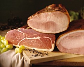 Three types of ham on a chopping board with juniper berries