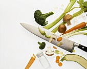 Fresh vegetables, partly cut; Knife; Salt cellar