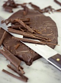 Chocolate and chocolate curls with knife on marble slab