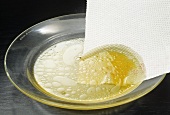 Removing fat from stock with kitchen towel
