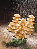 Fir tree biscuits being sprinkled with icing sugar