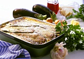 Moussaka in baking dish, ingredients beside it