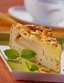 A piece of apple cake with custard topping & flaked almonds