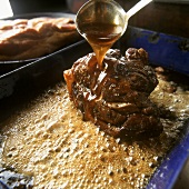 Basting meat in roasting dish with honey sauce