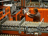 Worker at filling machine in drinks factory
