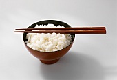 Boiled basmati rice in a red bowl with chopsticks