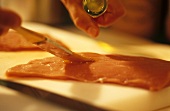 Brushing veal escalope with oil