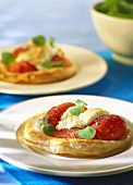 Puff pastries with tomatoes and coat's cheese on plates