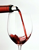 Pouring red wine from bottle with silver foil into glass