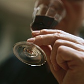 Hand lifting small red wine glass to mouth