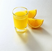 Ein Glas Orangensaft und zwei Orangenschnitze