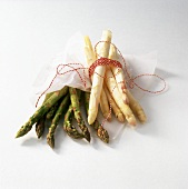 Green asparagus in paper and a bundle of white asparagus