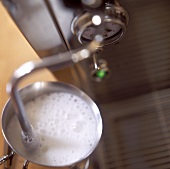 Frothing up milk in jug with espresso machine