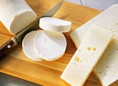 Various Greek cheeses on wooden chopping board