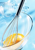 Egg broken into glass bowl with whisk