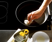 Rubbing a coated pan with oil-soaked cloth