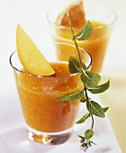 Mango smoothie in glasses with sprig of mint