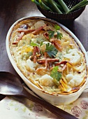 Potato & vegetable bake with strips of bacon in baking dish