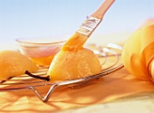 Spreading apricot jam on poached pear