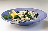 Rice stew with trout, spinach, lemon wedges and dill