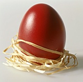 Rotes Ei, mit Stroh umwickelt