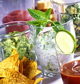 Various dips in glasses and tortilla chips