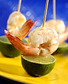 Shrimps and lime halves on skewers