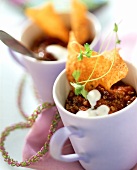 Chili con carne with sour cream, crisps and parsley