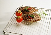 Peppered steaks and stuffed tomatoes on roasting rack