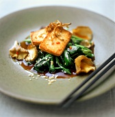 Fried tofu on spinach with sesame and mushrooms
