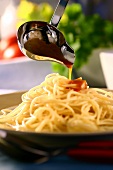 Pouring tomato sauce over spaghetti