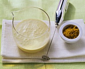 Curried cream dressing in glass; mini-whisk