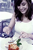 Woman eating spaghetti with tomato sauce and Parmesan