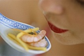 Woman holding spoonful of Asian shrimp soup