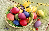 Easter eggs and sugar eggs in basket; spring flowers