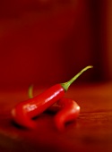 Two red chili peppers on wooden table