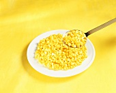 Grains of corn on plate and spoon